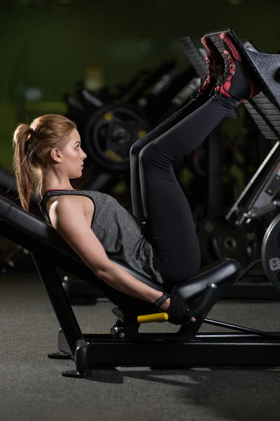 Sportive woman using weights press machine for legs. Gym. — Stock Photo, Image