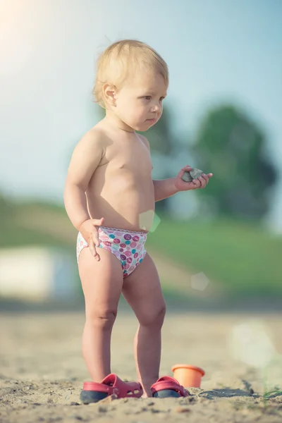 Niedliches Baby spielt mit Spielzeug am Sandstrand in Meeresnähe. — Stockfoto