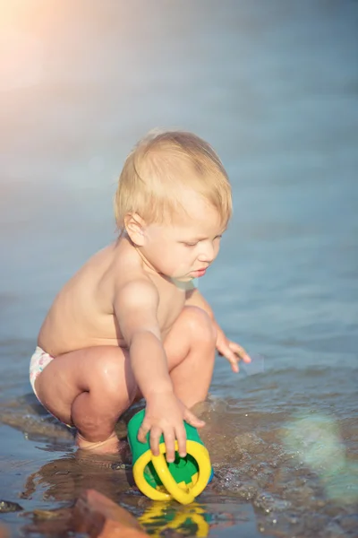 Carino bambino che gioca sulla spiaggia di sabbia e in acqua di mare . — Foto Stock