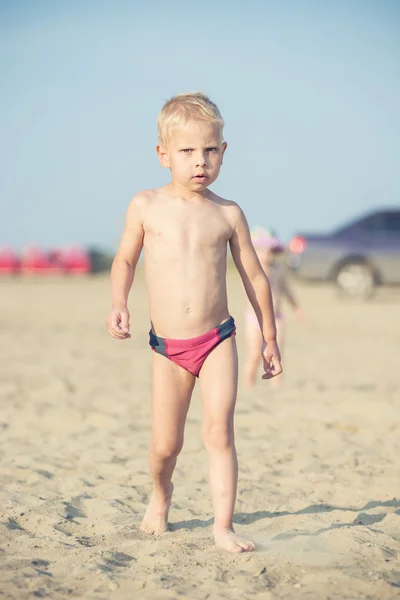 Carino il bambino che cammina sulla spiaggia sabbiosa vicino al mare. Costa oceanica . — Foto Stock