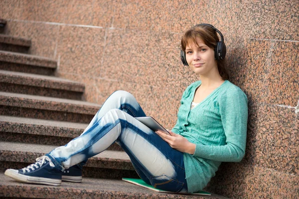 Linda jovem estudante com bloco de notas e fones de ouvido. Estudante exterior . — Fotografia de Stock