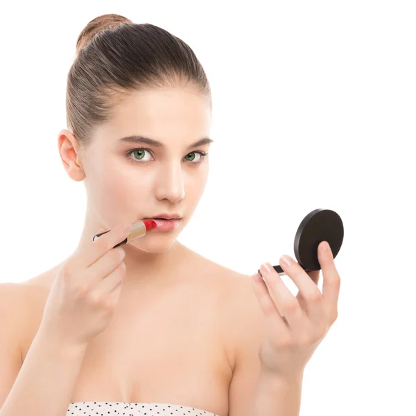 Junge brünette Frau mit perfekt sauberem Gesicht, die Lippenstift mit Spiegel aufträgt. isoliert auf einem weißen. — Stockfoto