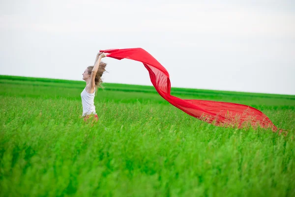 Jeune femme courant avec des tissus dans un champ vert. Femme avec écharpe . — Photo