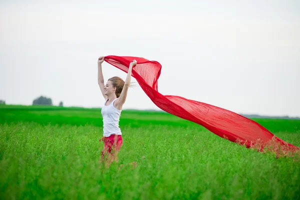 Young lady runing with tissue in green field. Woman with scarf. — Stock Photo, Image