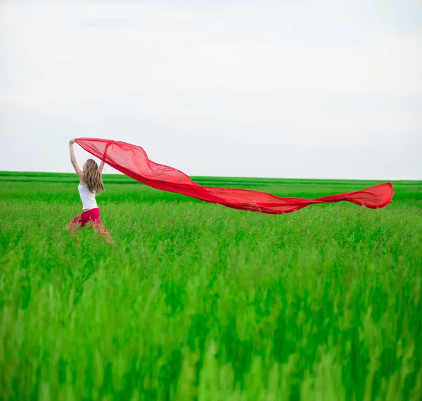 Jovencita corriendo con tejido en el campo verde. Mujer con bufanda . —  Fotos de Stock