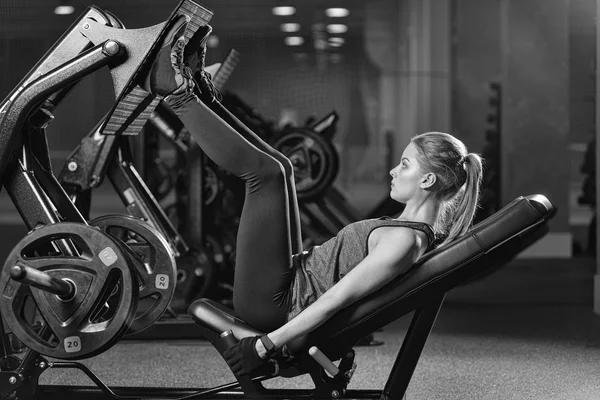 Mujer deportiva usando máquina de prensa de pesas para las piernas. Gimnasio . — Foto de Stock