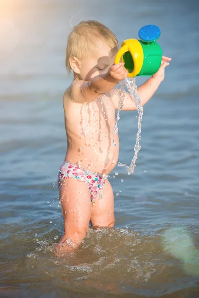 Carino bambino che gioca sulla spiaggia di sabbia e in acqua di mare . — Foto Stock