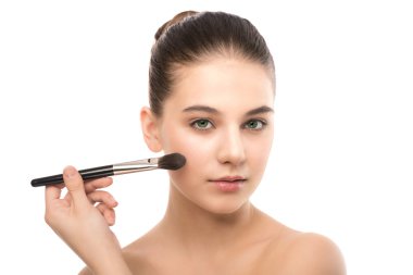 Temiz yüzü ile genç esmer kadın. Kız mükemmel cilt kozmetik fırça uygulamak. Beyaz izole.