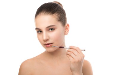 Temiz yüzü ile genç esmer kadın. Kız mükemmel cilt kozmetik fırça uygulamak. Beyaz izole.