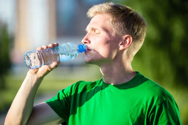 Yorgun bir adam içme suyu fitness sonra plastik bir şişe — Stok fotoğraf