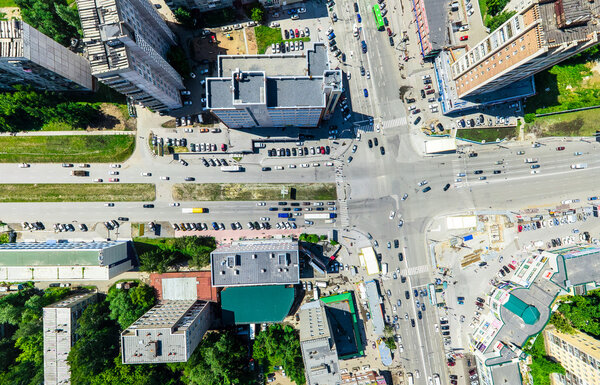 Aerial city view with crossroads and roads, houses, buildings, parks and parking lots, bridges. Urban landscape. Copter shot. Panoramic image.