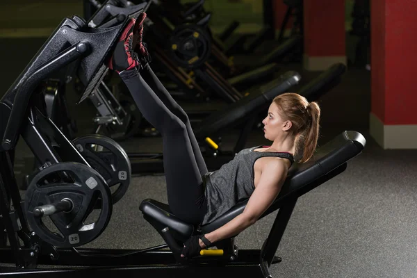 Mujer deportiva usando máquina de prensa de pesas para las piernas. Gimnasio . —  Fotos de Stock