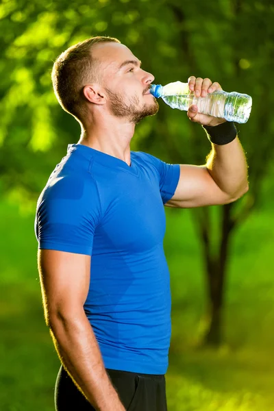 Atletische volwassen man drinking water uit een fles — Stockfoto