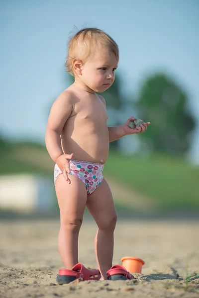 Lindo bebé jugando con juguetes en la playa de arena cerca del mar . —  Fotos de Stock