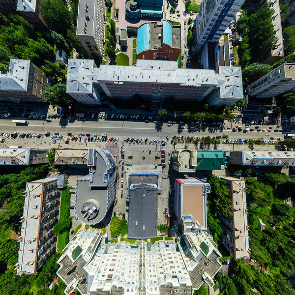 Aerial city view with crossroads and roads, houses, buildings, parks and parking lots, bridges. Copter shot. Panoramic image.