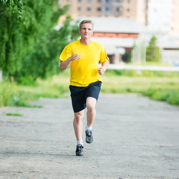 Sporty man jogging in city street park. Outdoor fitness. — Stock Photo, Image