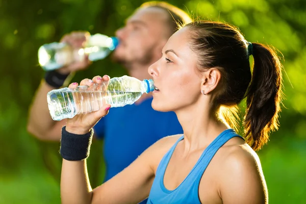 Hombre y mujer bebiendo agua de la botella después del ejercicio deportivo de fitness — Foto de Stock