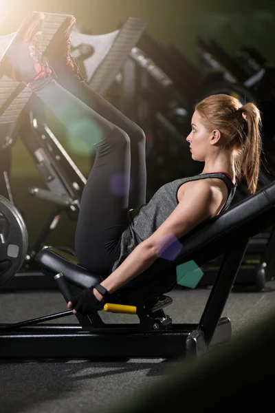 Mujer deportiva usando máquina de prensa de pesas para las piernas. Gimnasio . —  Fotos de Stock