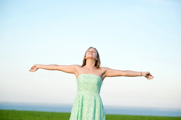 Felicidade mulher ficar ao ar livre sob a luz do sol do pôr do sol — Fotografia de Stock