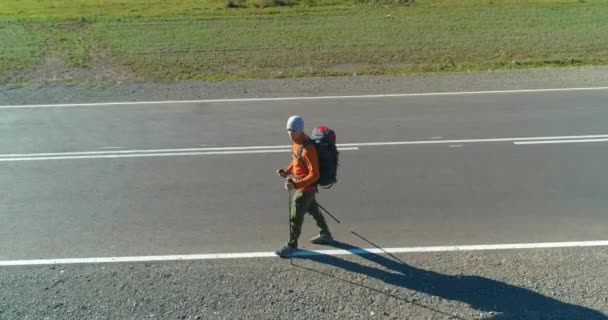 Vol au-dessus de l'auto-stoppeur touristique marchant sur la route asphaltée. Grande vallée rurale au jour d'été. Sac à dos randonneur gars. — Video