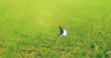 Yeşil çimlerin üzerinde sarı kırsal alanda not defteri olan bir adamın etrafında alçak yörünge uçuşları..