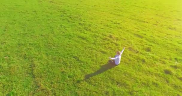 Låg omloppsbana flygning runt människan på grönt gräs med anteckningsblock på gul landsbygd fält. — Stockvideo
