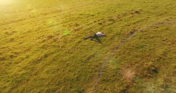 Vôo orbital baixo em torno do homem na grama verde com bloco de caderno no campo rural amarelo. — Vídeo de Stock