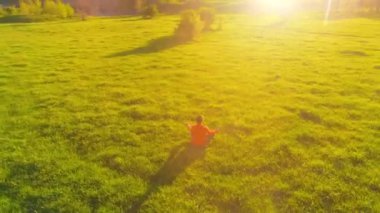 Yeşil çimlerde spor yogacısı üzerinde alçak irtifa radyal uçuş. Dağda gün batımı.