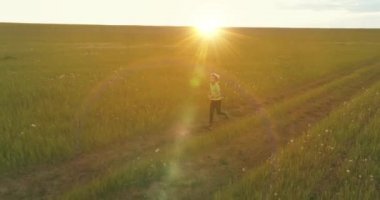 Sportif çocuk yeşil buğday tarlasında koşuyor. Kırsal çayırlarda akşam sporu alıştırmaları. Mutlu bir çocukluk sağlıklı bir yaşam biçimidir. Radikal hareket, güneş ışınları ve ot.