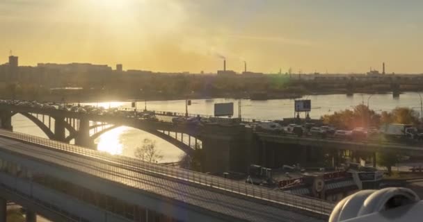 Timelaps van het stadsleven. Zonnestralen, blauwe lucht, rivier en brug over de horizon. Verkeersopstopping bij zonsondergang. Gemotoriseerde schuifbeweging — Stockvideo