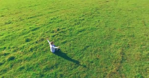 Niedriger Orbitalflug um den Menschen auf grünem Gras mit Notizblock auf gelbem Feld. — Stockvideo