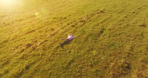 Nízká orbitální let kolem člověka na zelené trávě s poznámkovým blokem na žlutém venkovském poli. — Stock video