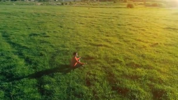 Vol radial à basse altitude au-dessus du yoga sportif homme à l'herbe verte parfaite. Coucher de soleil en montagne. — Video