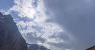 Yaz ya da sonbahar zamanı dağ vadisindeki destansı bulutların zamanı. Vahşi sonsuz doğa ve kar fırtınası gökyüzü. Kar zirvesinde güneş ışınları