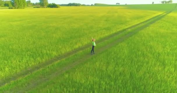 Спортивный ребенок стоит на зеленом пшеничном поле с поднятыми руками. Вечерние спортивные тренировки на сельском лугу. Счастливое детство это здоровый образ жизни. Радиальная панорама движения, солнечные лучи и — стоковое видео