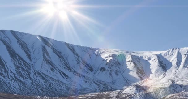 Timelapse de movimiento del sol en el cielo cristalino sobre la cima de la montaña de nieve. Hierba amarilla en el prado de otoño. Naturaleza salvaje sin fin. — Vídeos de Stock