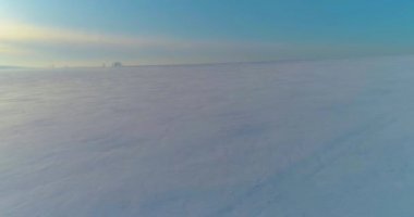 Soğuk kış manzarası kutup bölgesi, karla kaplı ağaçlar, ufukta buz nehri ve güneş ışınları. Aşırı düşük sıcaklık havası.