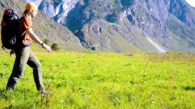 Sırt çantası ile yeşil dağ çayır üzerinde yürüyen adam hiking. Yaz spor ve eğlence kavramı.