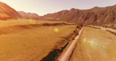 Güneşli yaz sabahında havadan kırsal dağ yolu ve çayır. Asfalt karayolu ve nehir.