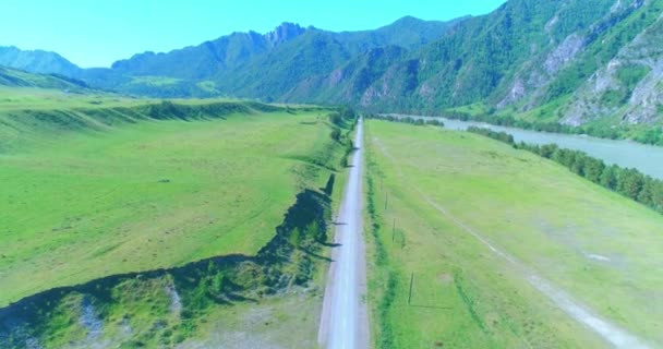 Camino de montaña rural aéreo y prado en la soleada mañana de verano. Autopista del asfalto y río. — Vídeo de stock