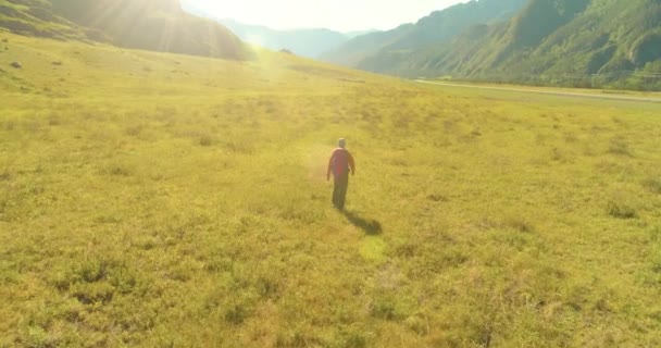 緑の山のフィールドを横断するバックパックハイキング観光客の上のフライト。夏の日の巨大な田舎の谷. — ストック動画