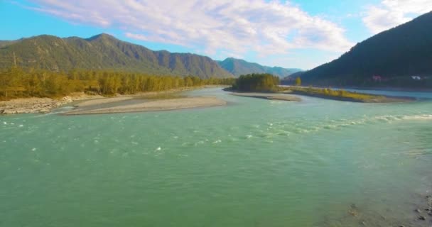 Vol à basse altitude au-dessus d'une rivière de montagne fraîche et rapide avec des rochers au soleil matin d'été. — Video