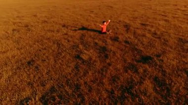 Yeşil çimlerde spor yogacısı üzerinde alçak irtifa radyal uçuş. Dağda gün batımı.