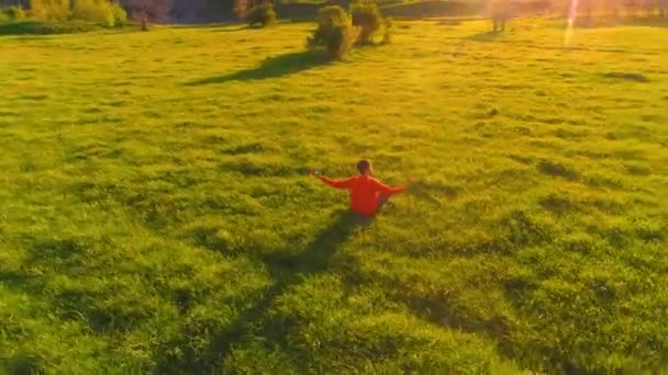 Vuelo radial de baja altitud sobre el hombre del yoga del deporte en hierba verde perfecta. Puesta de sol en montaña. — Vídeos de Stock