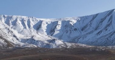 Güneşin kar dağının tepesinde kristal berrak gökyüzünde hareketinin zamanı. Sonbahar otlağında sarı çimenler. Vahşi sonsuz doğa..