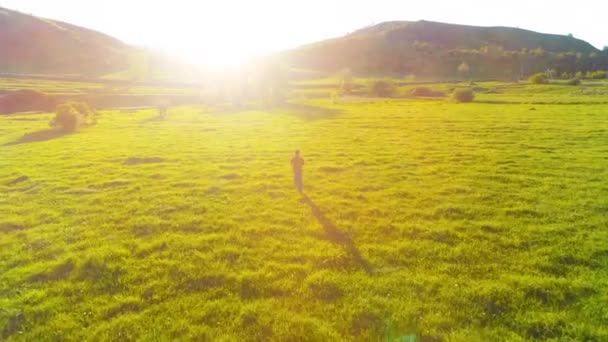 Flight over sport man at perfect green grass meadow. Sunset in mountain — Stock Video