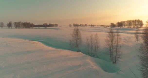 Letecký pohled na studenou arktickou krajinu, stromy s mrazivým sněhem, ledovou řekou a slunečními paprsky nad obzorem. Extrémní nízké teploty počasí. — Stock video