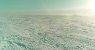 Soğuk kış manzarası kutup bölgesi, karla kaplı ağaçlar, ufukta buz nehri ve güneş ışınları. Aşırı düşük sıcaklık havası.