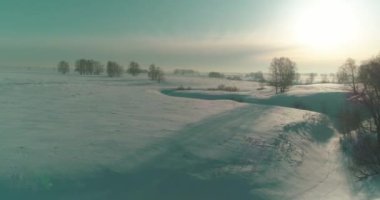 Soğuk kış manzarası kutup bölgesi, karla kaplı ağaçlar, ufukta buz nehri ve güneş ışınları. Aşırı düşük sıcaklık havası.