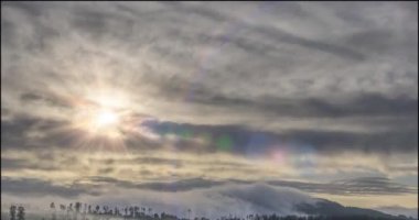 Akşam güneşlerinin zamanı dağlardaki soğuk, sisli bulutların arasından yükseliyor. Dağ sisinde gün batımı.